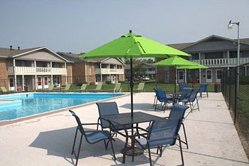 a swimming pool with patio furniture and umbrellas